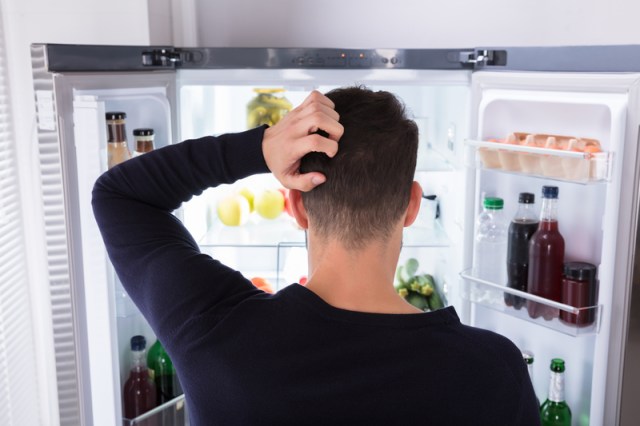 Confused Man Looking At Food In Refrigerator